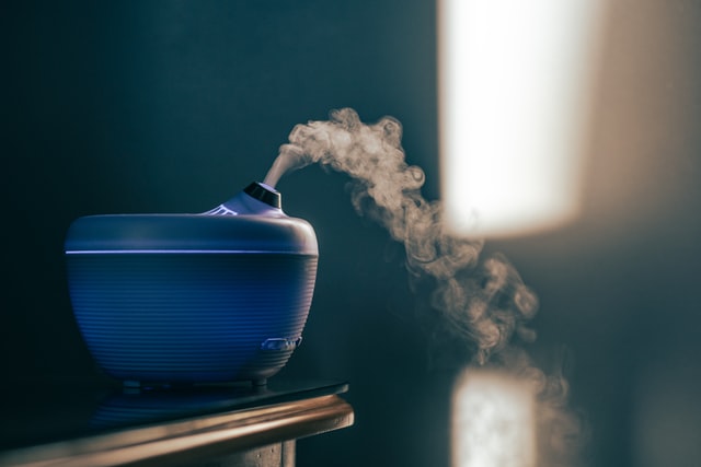 Blue diffuser on table for article about the difference between candles incense and diffusers 